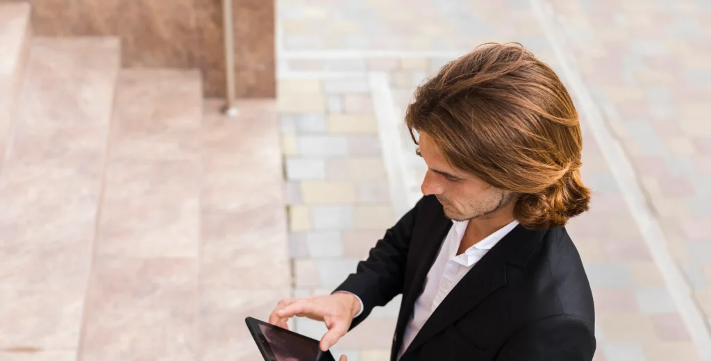 Ein Mitarbeiter im Business-Outfit nutzt am Smartphone ein Tool zur mobilen Zeiterfassung